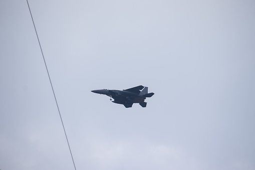DAEGU, REPUBLIC OF KOREA - JUNE 15, 2022 : A fighter jet flying low before landing with power lines and cloudy sky background.