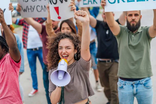 istock Young woman shouting on megaphone during a protest 1408443966