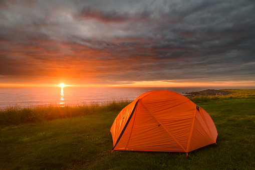 Camping at the ocean with a midnight sunset and dramatic skies