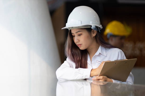 istock Young architect or engineer working in an office is writing a note on the design of a building model on a notepad. 1408448947