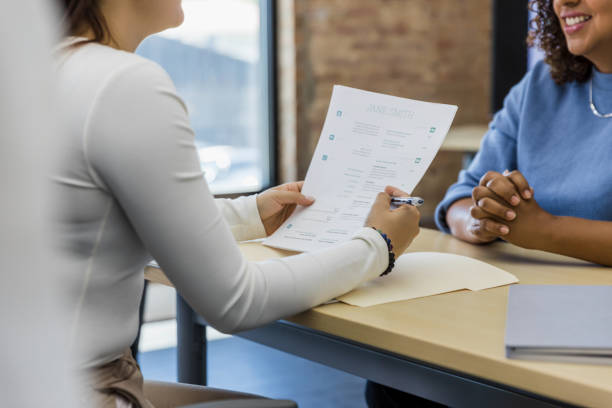 Woman clasps hands and smiles during interview The unrecognizable woman smiles and clasps her hands during the interview. good cv stock pictures, royalty-free photos & images