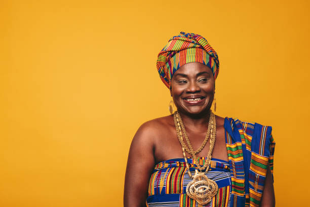 mujer ghanesa sonriente con ropa tradicional elegante en un estudio - african culture fotografías e imágenes de stock