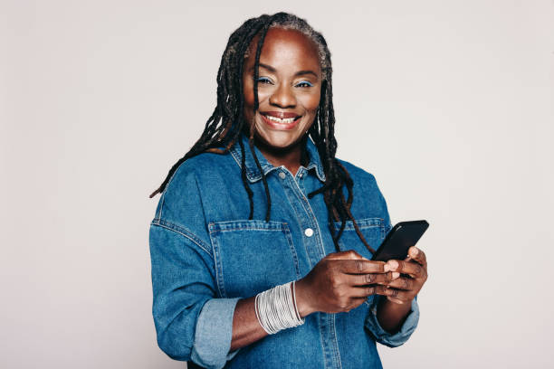 istock Happy mature woman smiling while holding a smartphone 1408451628
