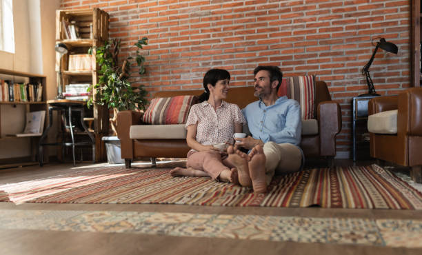 istock Middle aged married couple is relaxing at home lying on carpet with coffee 1408452460