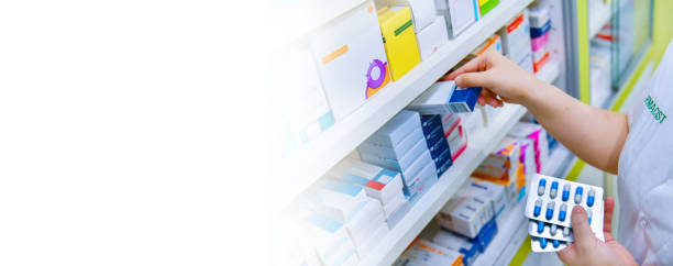 Pharmacist holding medicine box and capsule pack in pharmacy drugstore stock photo