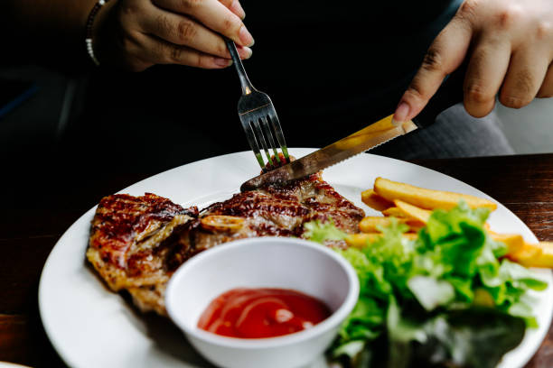 istock eating steak on white plate with fork and knife on his hands 1408463389