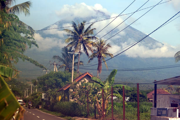 Local man riding motorcycle in Amed, a village on the east coast of Bali. In the distance the mount Agung, an active volcano and the highest point on Bali at 3031 mt.