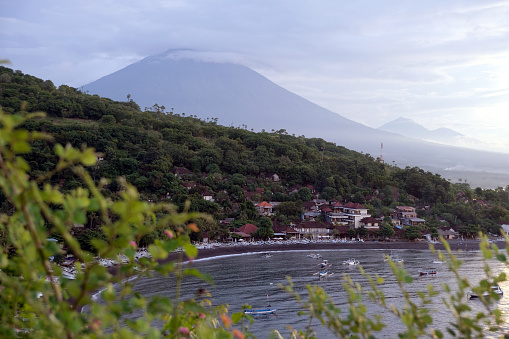 View of black sand beach on Amed coast and mount Agung, an active volcano and the highest point on Bali at 3031 mt.