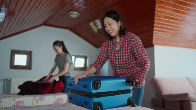 Two multi-ethnic female tourists unpacking their luggage at their rental home for home-staying