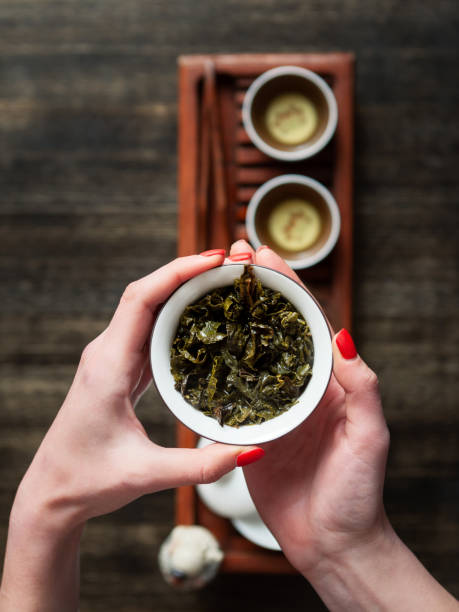 mains tenant chawan (bol à thé) avec oolong vert. - chinese tea photos et images de collection