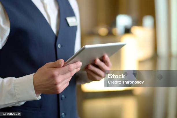 Digital Tablet In Hands Of Young Male Receptionist Of Luxurious Modern Hotel Stock Photo - Download Image Now
