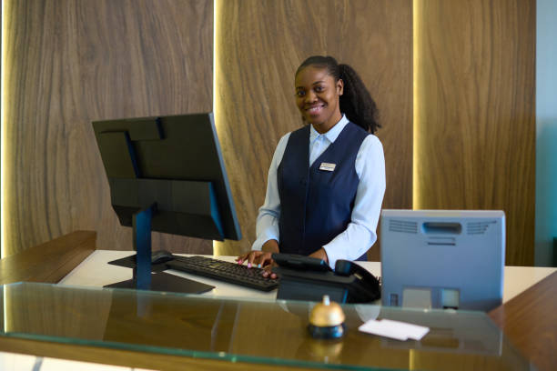 istock Happy young successful female receptionist in uniform standing by counter 1408468592