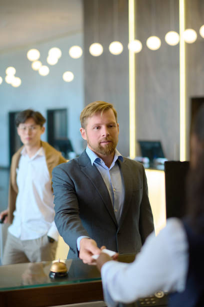 istock Confident businessman in formalwear taking keycard held by receptionist 1408468626