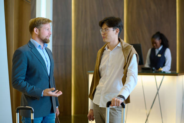 istock Two young intercultural businessmen with suitcase having discussion in lounge 1408468628