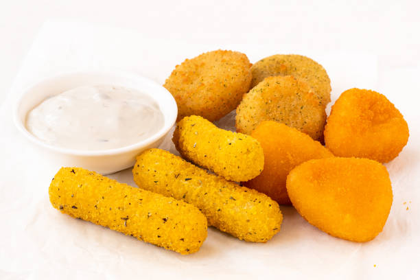 istock Selection of breaded fried cheese on a white baking paper with white dip. 1408470285