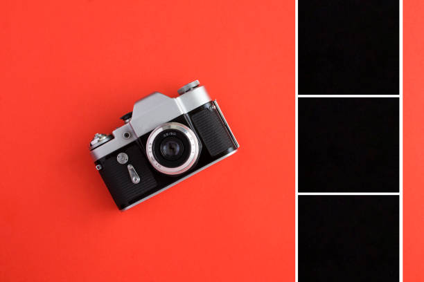 Old camera and black squares for photo or text on the red background. Top view. Copy space.