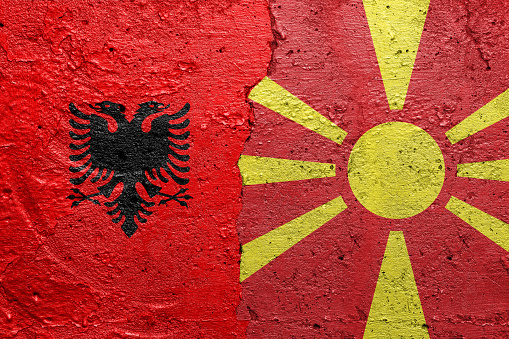 Albania and North Macedonia flags  - Cracked concrete wall painted with a Albanian flag on the left and a North Macedonian flag on the right