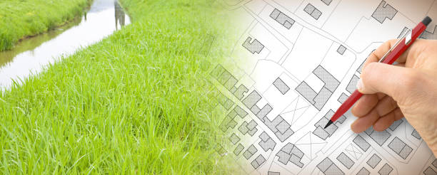 istock Planning a new city - concept image with hand drawing an imaginary cadastral map of territory with buildings, fields and roads against a green area with a creek 1408487733