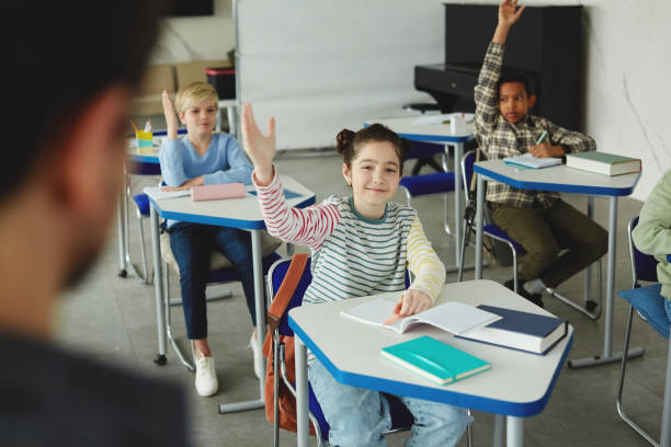 istock Cute Girl Raising Hand in School 1408507400