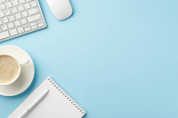 istock Business concept. Top view photo of workspace keyboard computer mouse open planner pen and cup of frothy coffee on saucer on isolated pastel blue background 1408507546