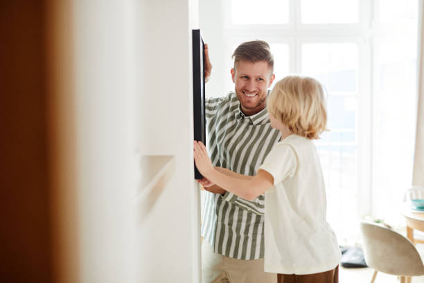 istock Father and Son Hanging Picture Back View 1408510252