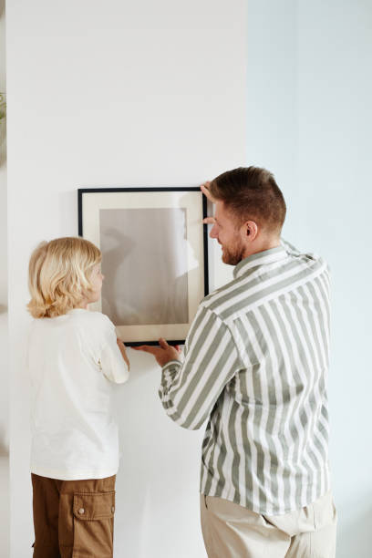istock Father and Son Hanging Picture at Home 1408510256