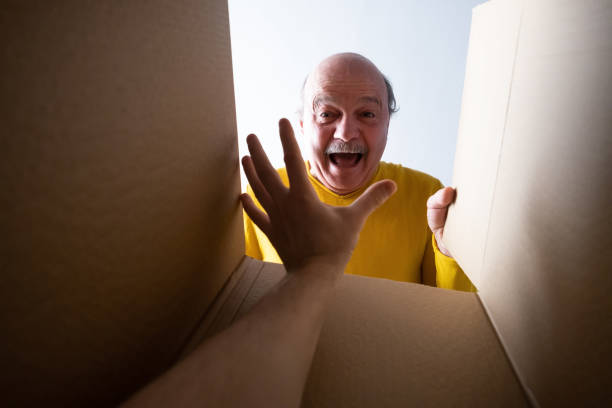 istock man unpacking, opening carton box and looking inside. Somebody attack him. 1408510881