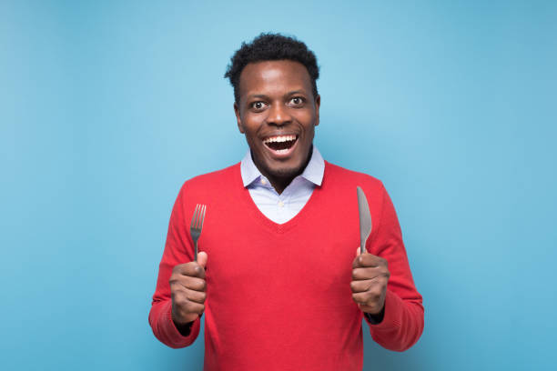 istock Hungry african young man holding fork and knife on hand ready to eat 1408512031