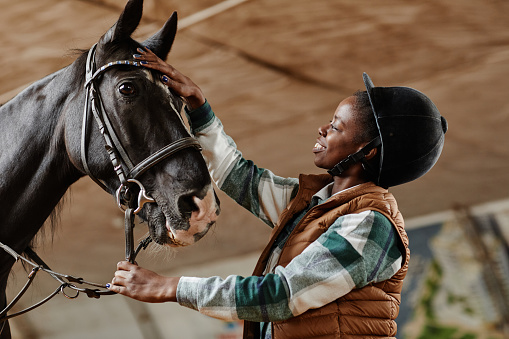 Riding school, a young jockey is riding a beautiful grey-haired thoroughbred horse in his dressage class, they are inside a fence and no one else can be seen.