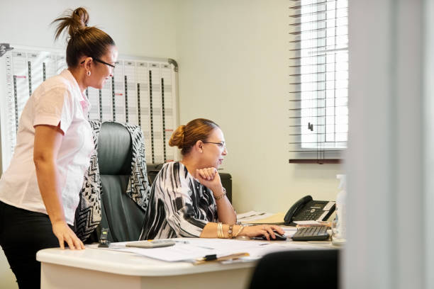 istock Businesswoman working on computer with a colleague standing by in office 1408514127