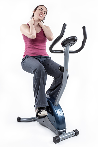 Shot of a young girl in pain on an exercise bike in the studio.