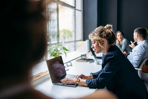 Group of four business people talking and working together in a modern office with big window.