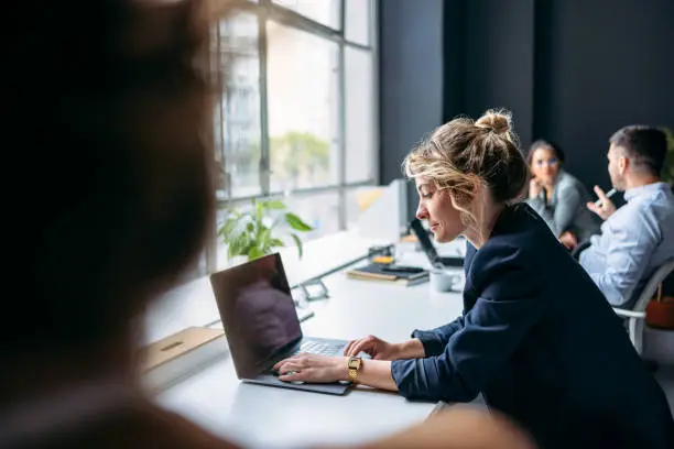 Photo of Businesspeople Sitting In A Row At Office Desk And Working On Their Laptop Computers