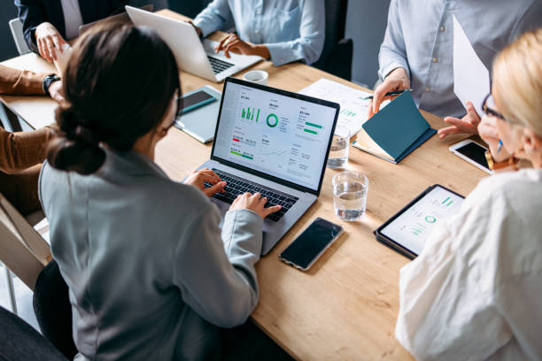 Group of Businesspeople Analyzing Business Graphs and Documents Together