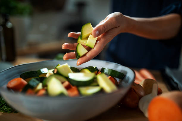 Preparing a roasted root vegetables A chef is preparing and chopping root vegetables for roasting in oven in a cozy and warm home kitchen. courgette stock pictures, royalty-free photos & images