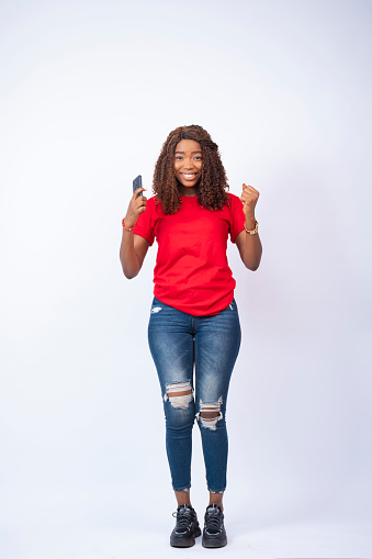 happy and excited young black lady holding her phone