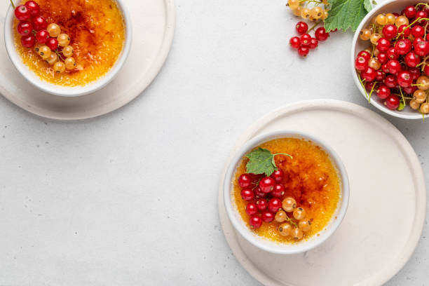 creme brulee, cream brulee, burnt cream with currant in ramekins. traditional french vanilla cream dessert with caramelised sugar on top. homemade dessert with berries. top view, copy space. - custard creme brulee french cuisine crema catalana imagens e fotografias de stock