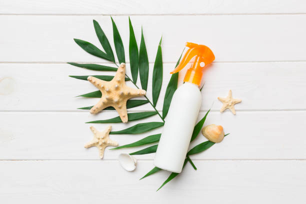 Sunscreen spray bottle. Bottle with sun protection cream and sea shells with tropical green leaf on color background, top view Sunscreen spray bottle. Bottle with sun protection cream and sea shells with tropical green leaf on color background, top view. shell starfish orange sea stock pictures, royalty-free photos & images