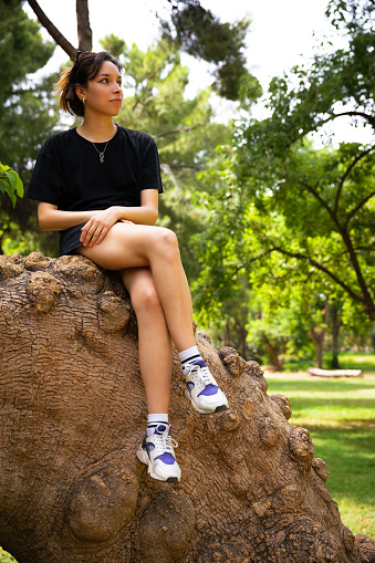 Young woman sitting on tree