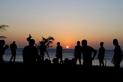 Silhouette of group of boys play at beach and sunset