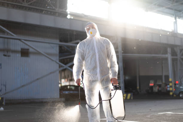 istock Man dressed white protective overalls spraying surface antibacterial sanitizer sprayer during quarantine 1408536646
