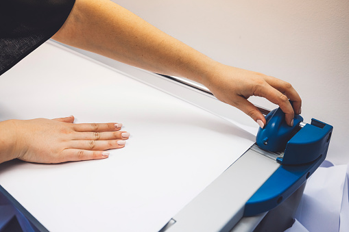 Unrecognizable woman hands cutting paper with a special blade.