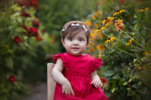 Cute latin american one year-old girl smiling at camera surrounded by flowers - Buenos Aires - Argentina