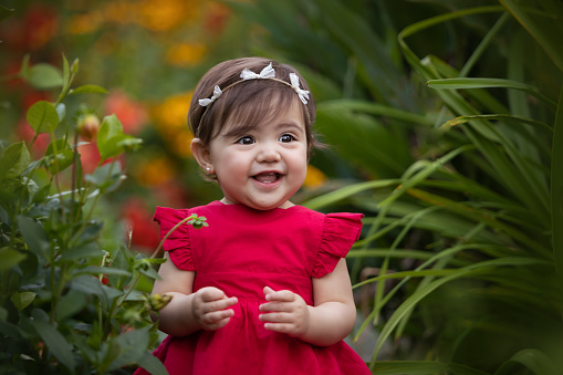 Cute latin american one year-old girl smiling at camera surrounded by flowers - Buenos Aires - Argentina