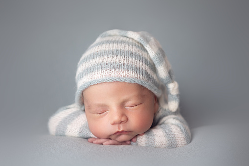 Little baby boy with knitted hat in a basket, happily smiling and looking at camera, isolated studio shot