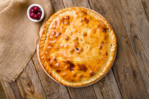 Ossetian pie with cherry on old wooden table