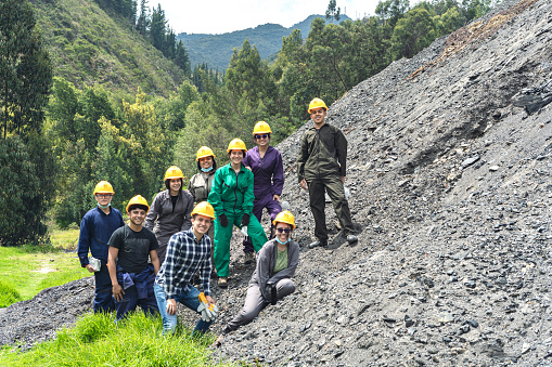 Group of mining engineering students and miners on a mountain looking at the camera while smiling.
