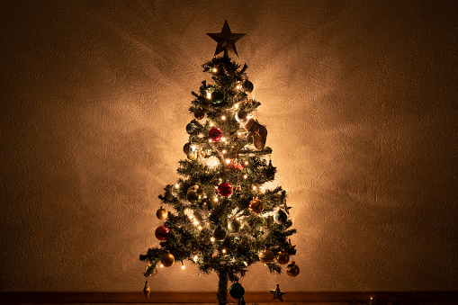 Illuminated and decorated artificial Christmas tree on the wall of the living room