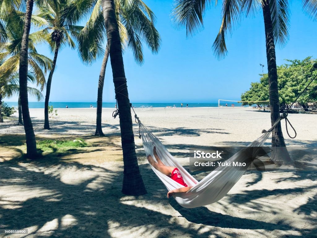 Young woman relaxing in hammock on the beach of Santa Marta, Colombia Santa Marta - Colombia Stock Photo
