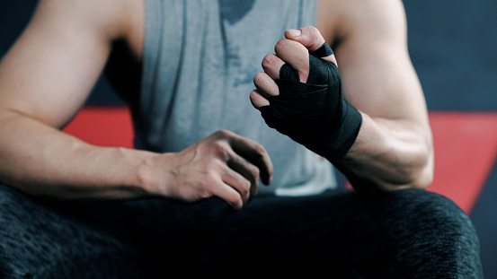 An Asian male instructor wrapping his hand before going to a fitness session.
